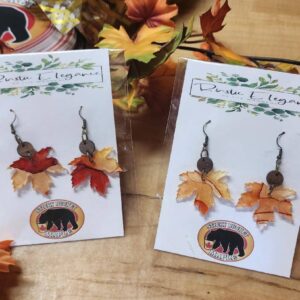 Two Maple Leaf Shaped Earrings Set on a Table